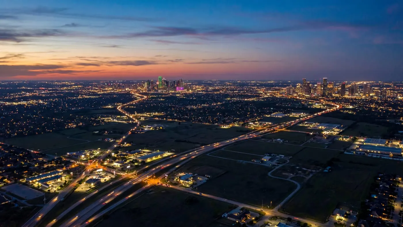 Panoramic aerial view of Texas cities connected by illuminated highways at twilight showing urban growth