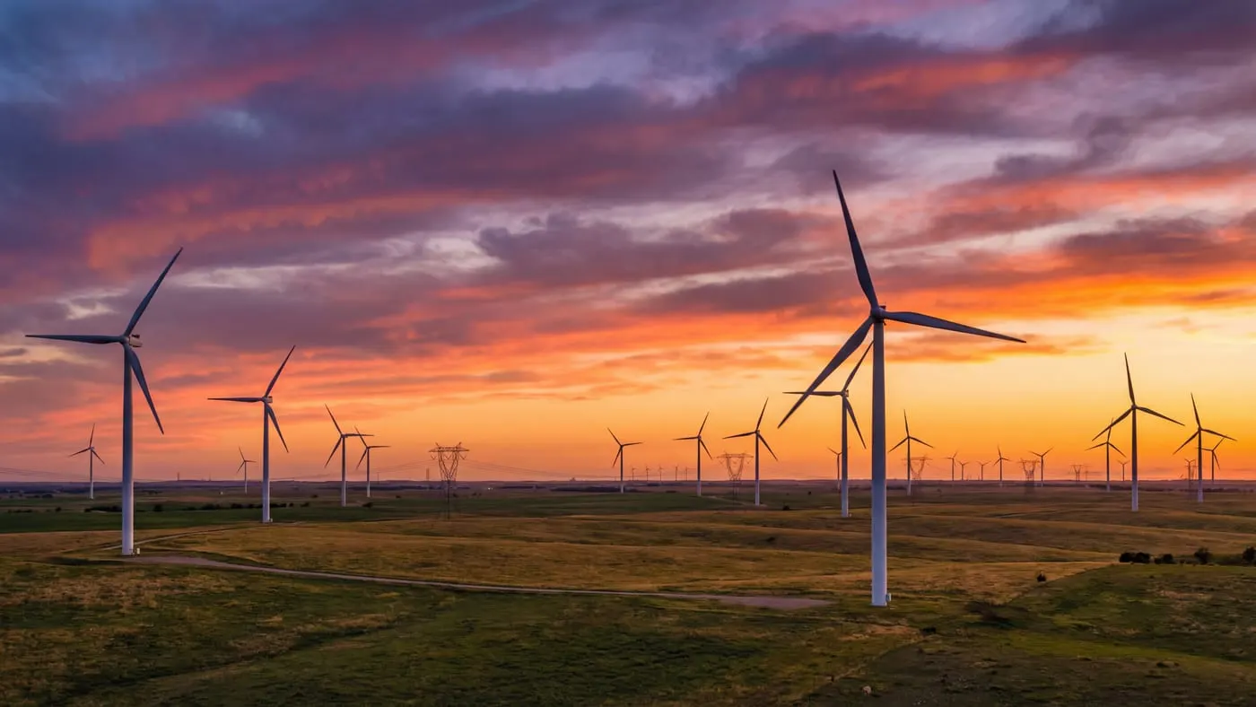 Texas wind farm at sunset with rows of turbines on rolling plains and dramatic orange purple sky